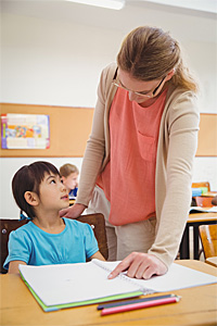 teacher helping pupil in classroom